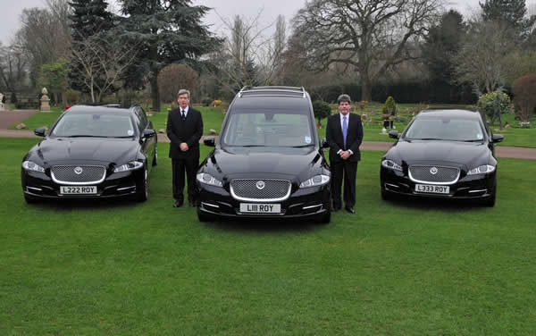 Jaguar XJ hearse and two XJ limousines and two funeral directors standing along side.