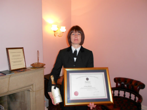 Sabrina Rhodes with exam certificate and bottle of champagne